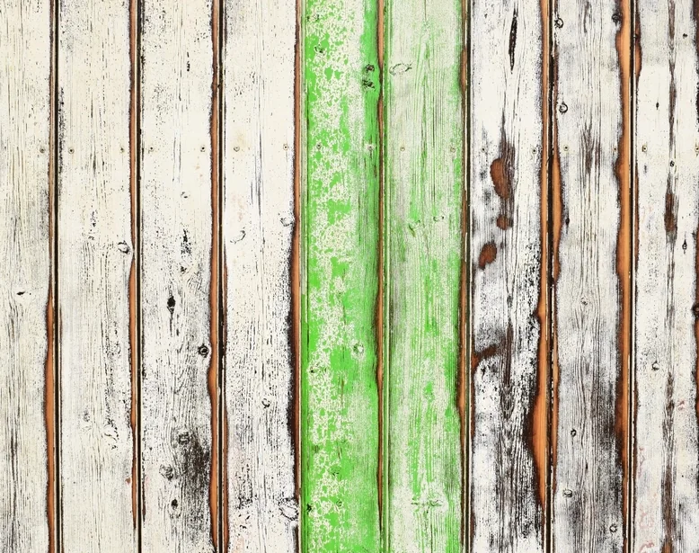Old deck boards with green paint flaking off and gaps open between them