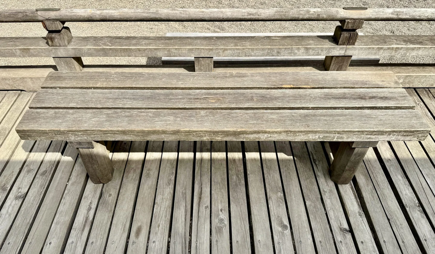Weathered grey slat deck with a simple wooden bench across it
