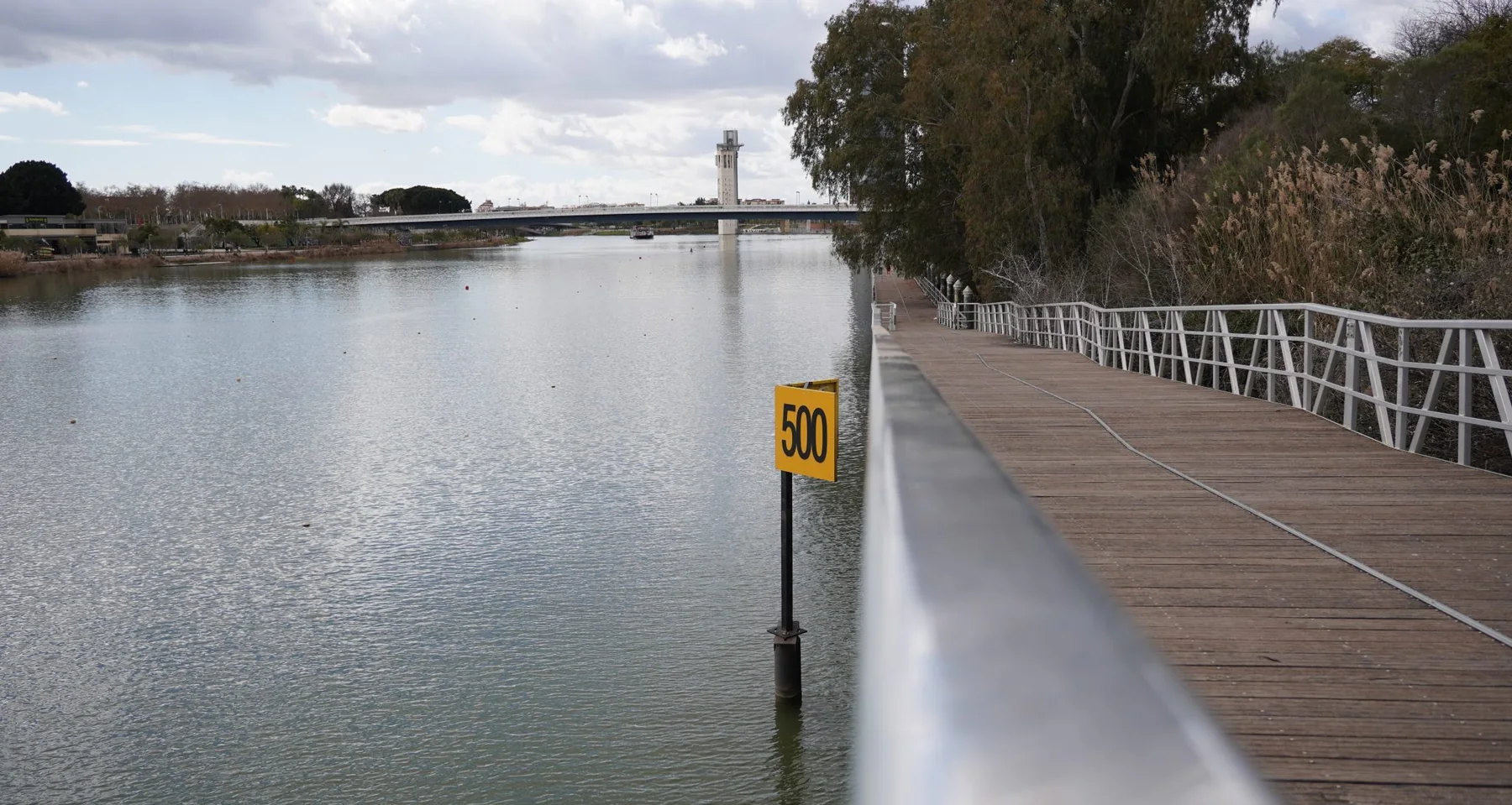 White deck rail running along a timber walkway beside open water